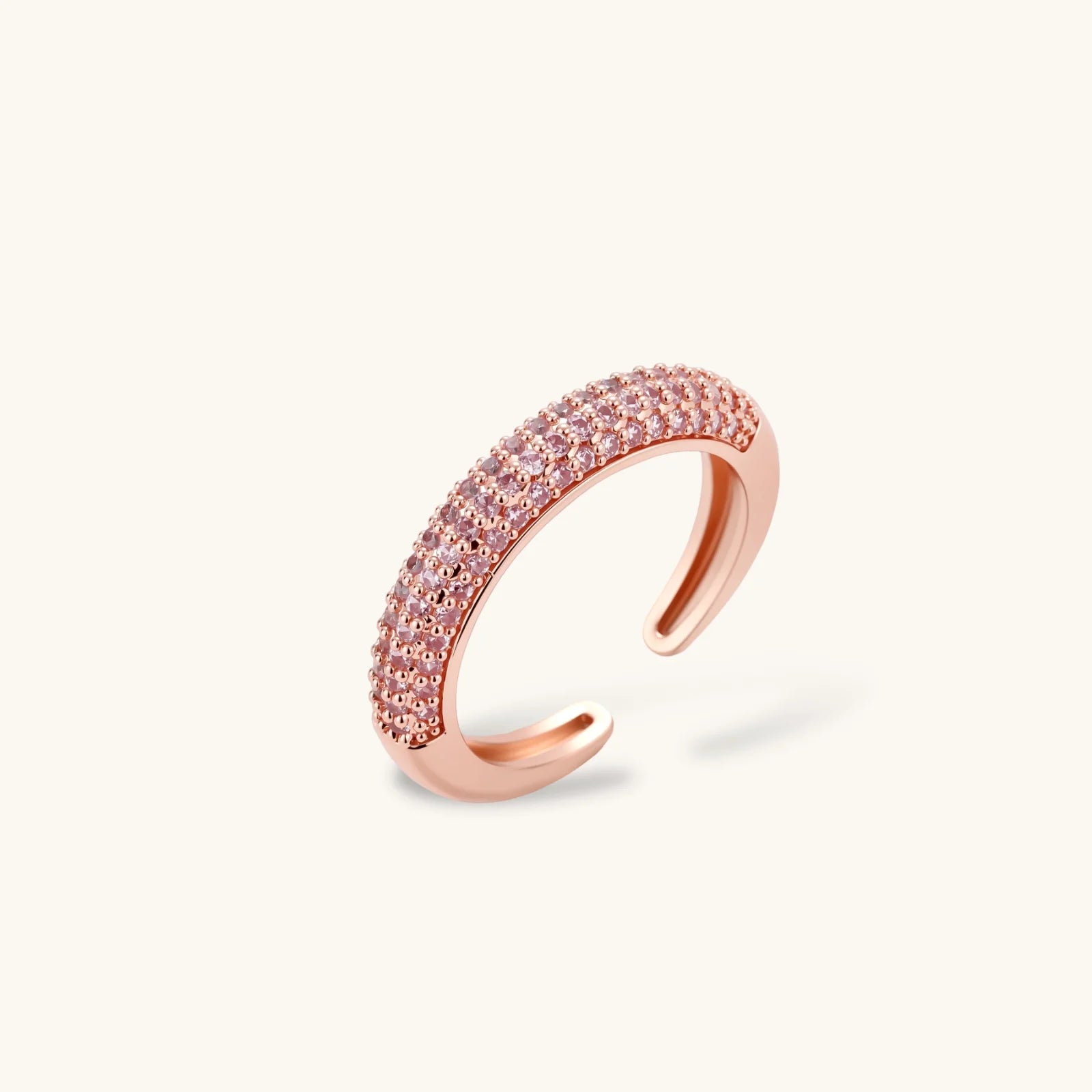 Rose gold pavé zirconia bar necklace, hoop earrings, and open ring set with pink stones on cream background.