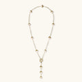 Gold-plated lariat necklace with baroque pearls and textured caps on cream background, showing adjustable Y-shaped design.