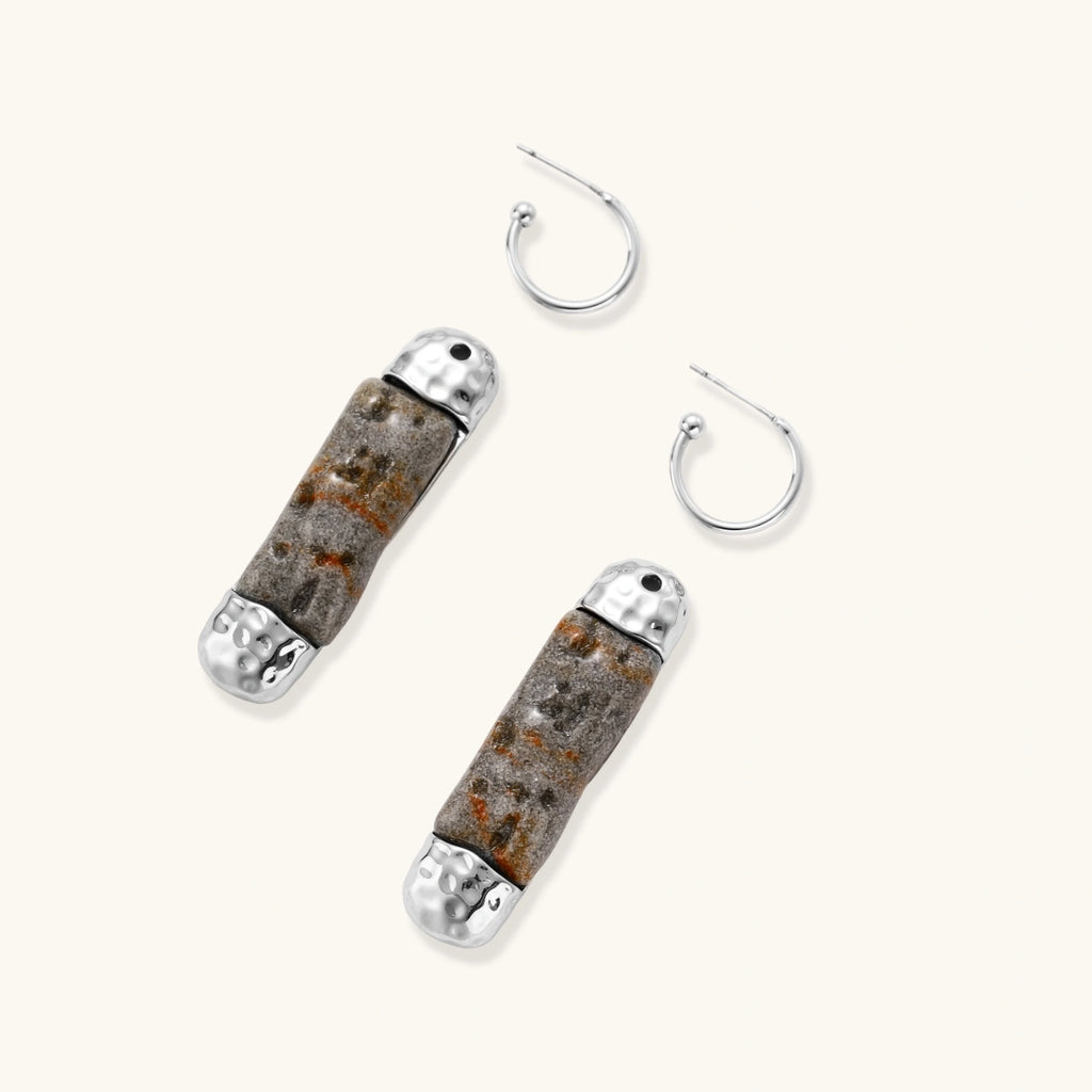 Cylindrical resin earrings with gray stone-like patterns and silver-toned metal caps, hanging against white background