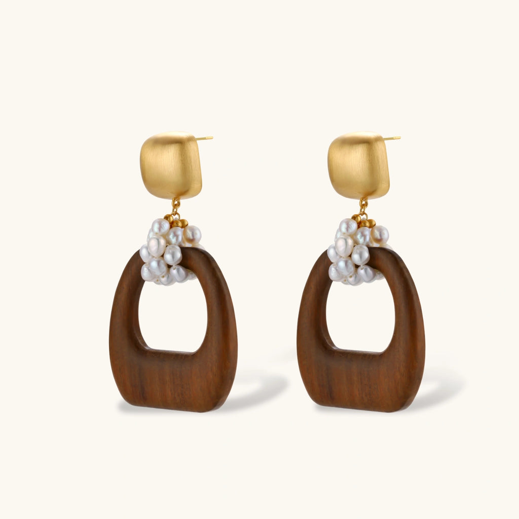 Gold-plated stud earrings with pearl clusters and organic brown wooden hoops on cream background
