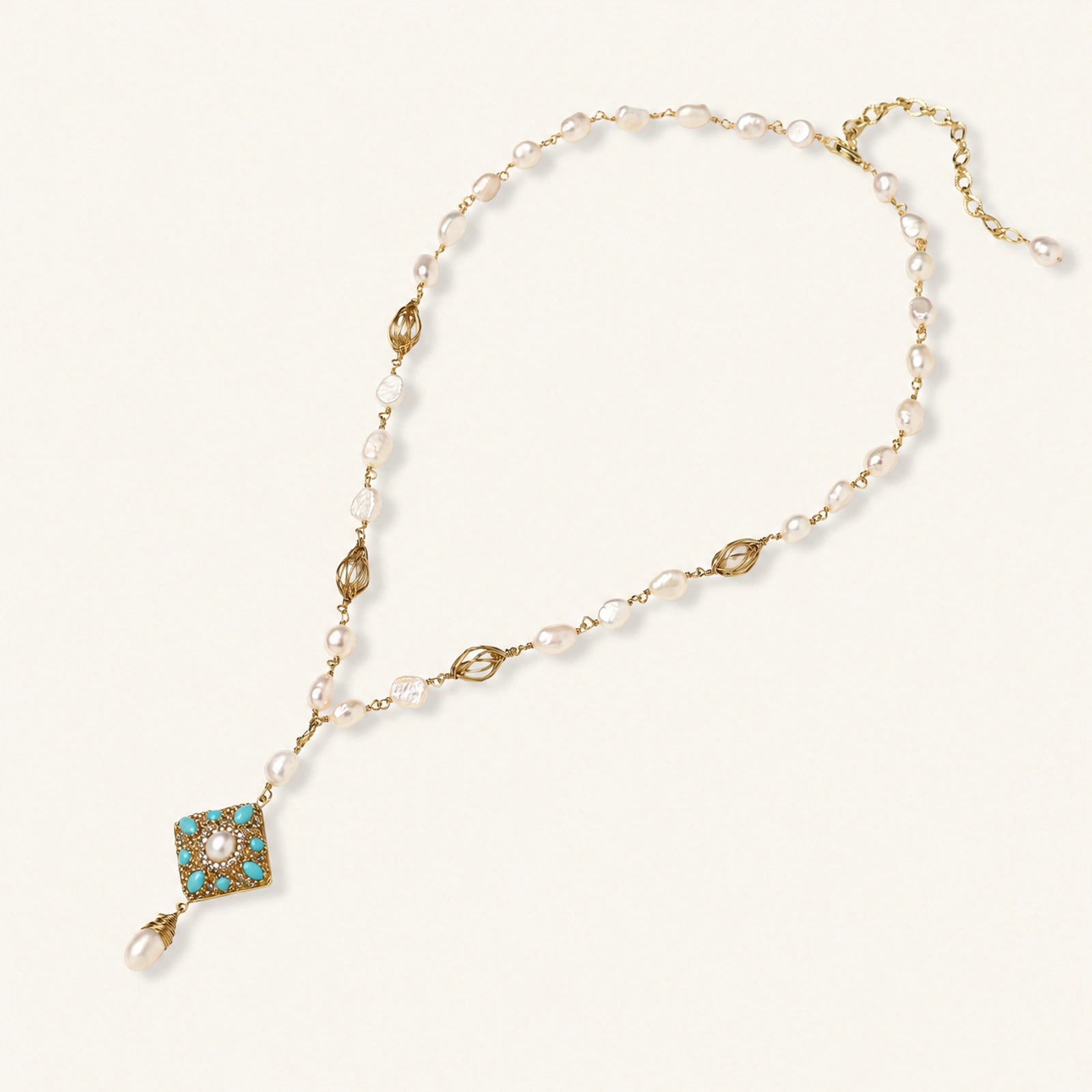 Y-shaped necklace with freshwater pearls, gold filigree stations, and ornate diamond-shaped centerpiece with pearl drop